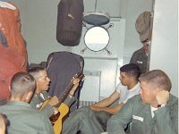 LT Pete Fleury playing guitar and LT Jim Thomson and LT Cecil Gardner listening; others not identified
